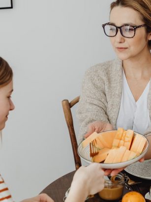 Mother and daughter enjoying a healthy breakfast together with fresh fruits and juice.